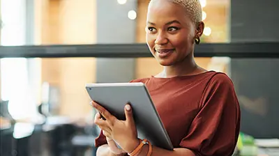 New Year’s Resolution: Digitize the Application and Renewal Process A woman holding a tablet in her hands while looking off to the side
