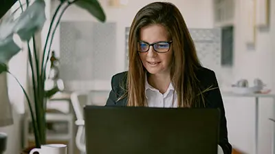 Participate in the 2022 State of Insurance Renewals Survey A woman wearing glasses and looking down at her laptop