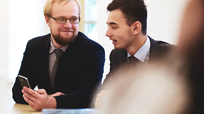 A man showing a colleague something on his phone