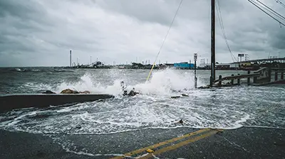 Waves crashing over a fence onto a road